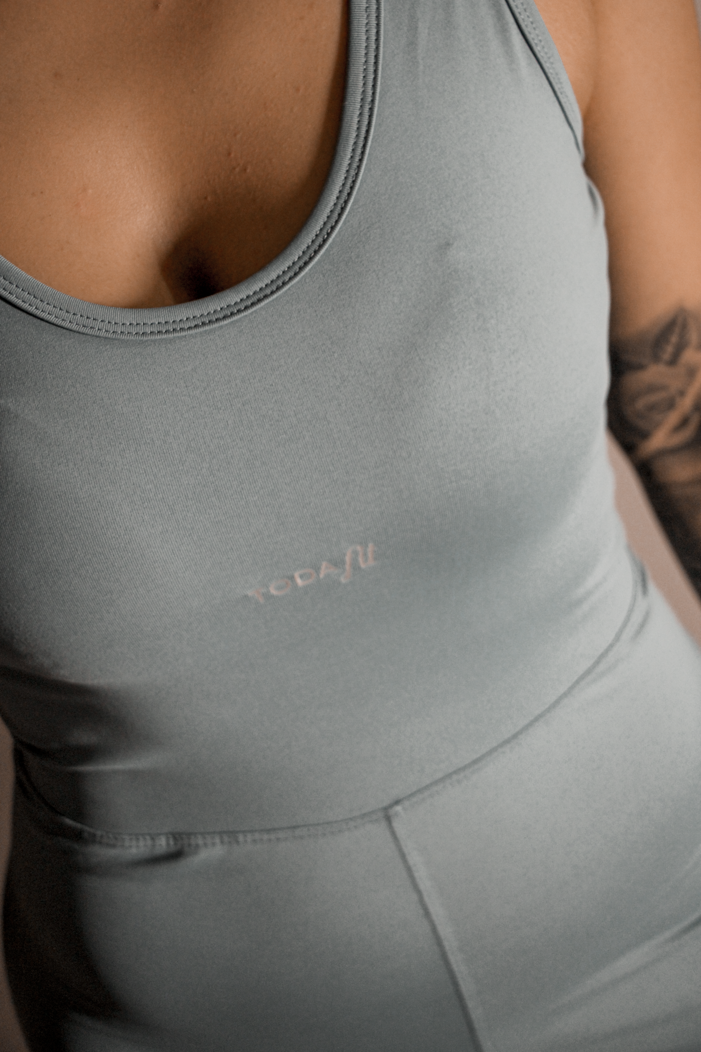 Detalhe do macaquinho verde TodaFit em close, ressaltando tecido e acabamento.